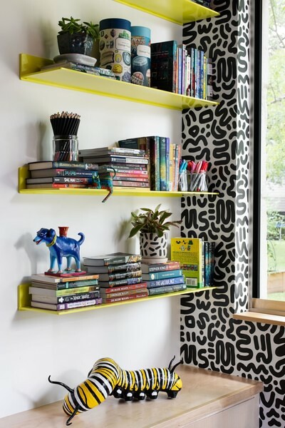 This cozy den area flaunts metal floating shelves in Bananarama yellow against modern wallpaper. Design: Hey Now Interiors, Photo: Avery Nicole Photography