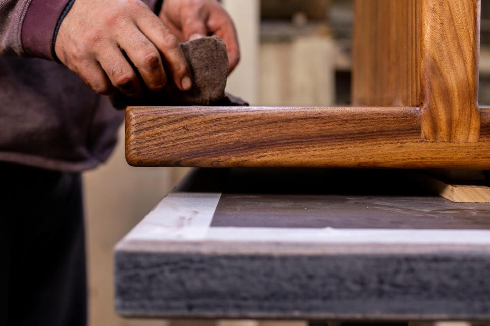 Closeup of carpenter coating a wooden table with protective flaxseed oil