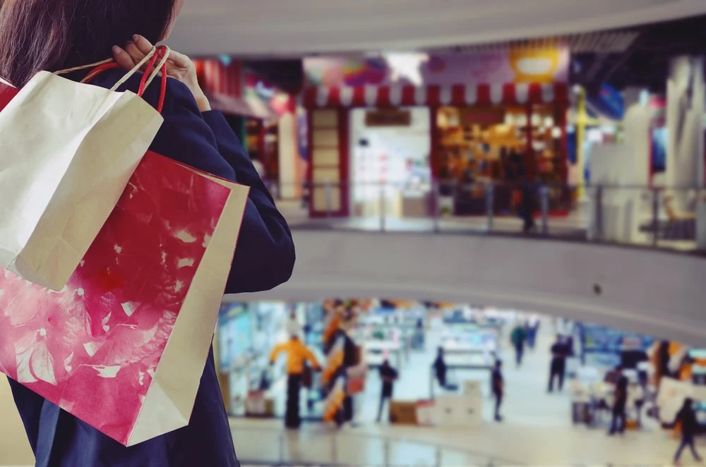A woman holds a shopping bag over her shoulder at a shopping mall