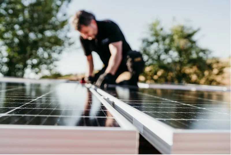 A technical specialist is installing solar panels on the roof.