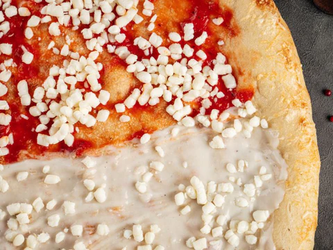 Half-tomato, half-white sauce pizza topped with cheese bits.