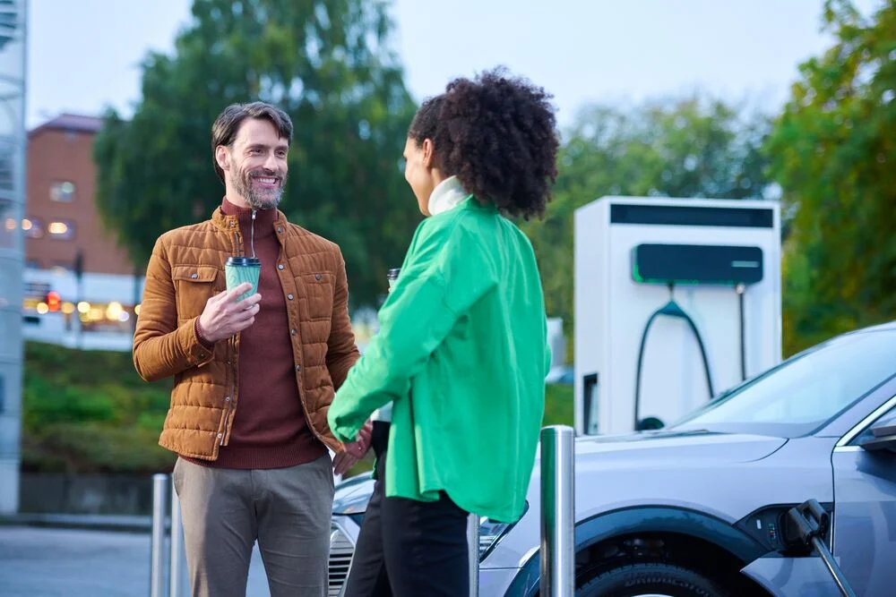 Two EV drivers chat while their EVs charge at an EVBox Troniq Modular charging station