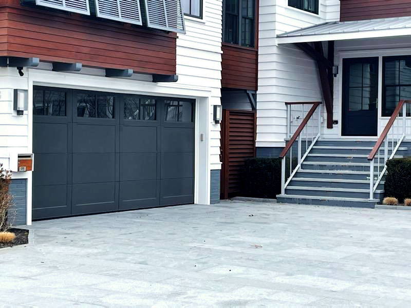A navy blue garage door installed on a white house.