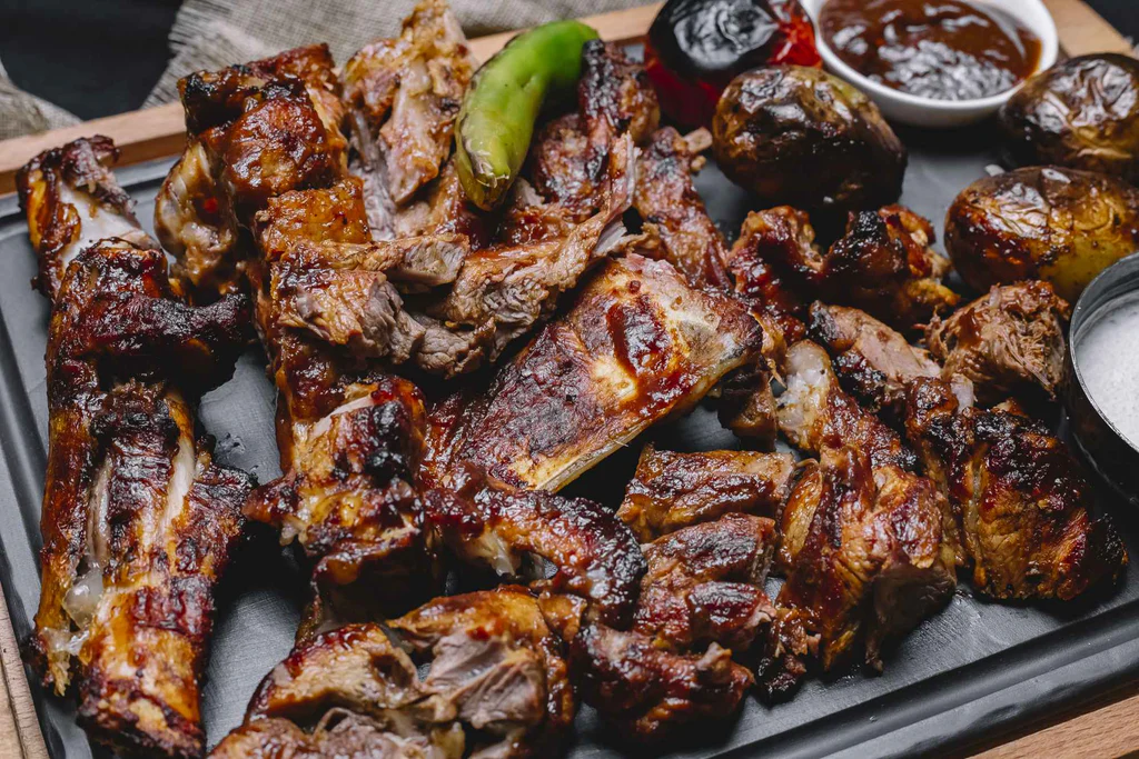 A tray of grilled ribs, roasted potatoes, green pepper, and assorted sauces.A tray of grilled ribs, roasted potatoes, green pepper, and assorted sauces.A tray of grilled ribs, roasted potatoes, green pepper, and assorted sauces.