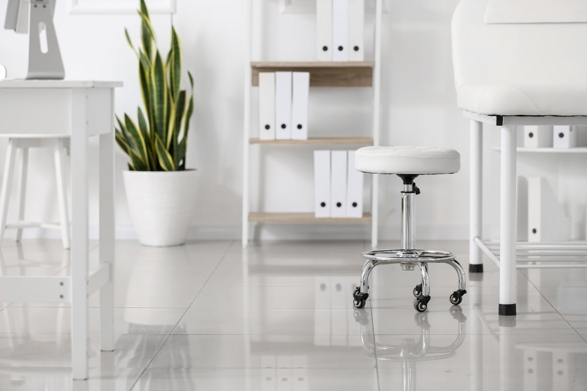 Drafting stool with a cushioned seat in a doctor's office, highlighting the ergonomic features and versatility of drafting chairs.