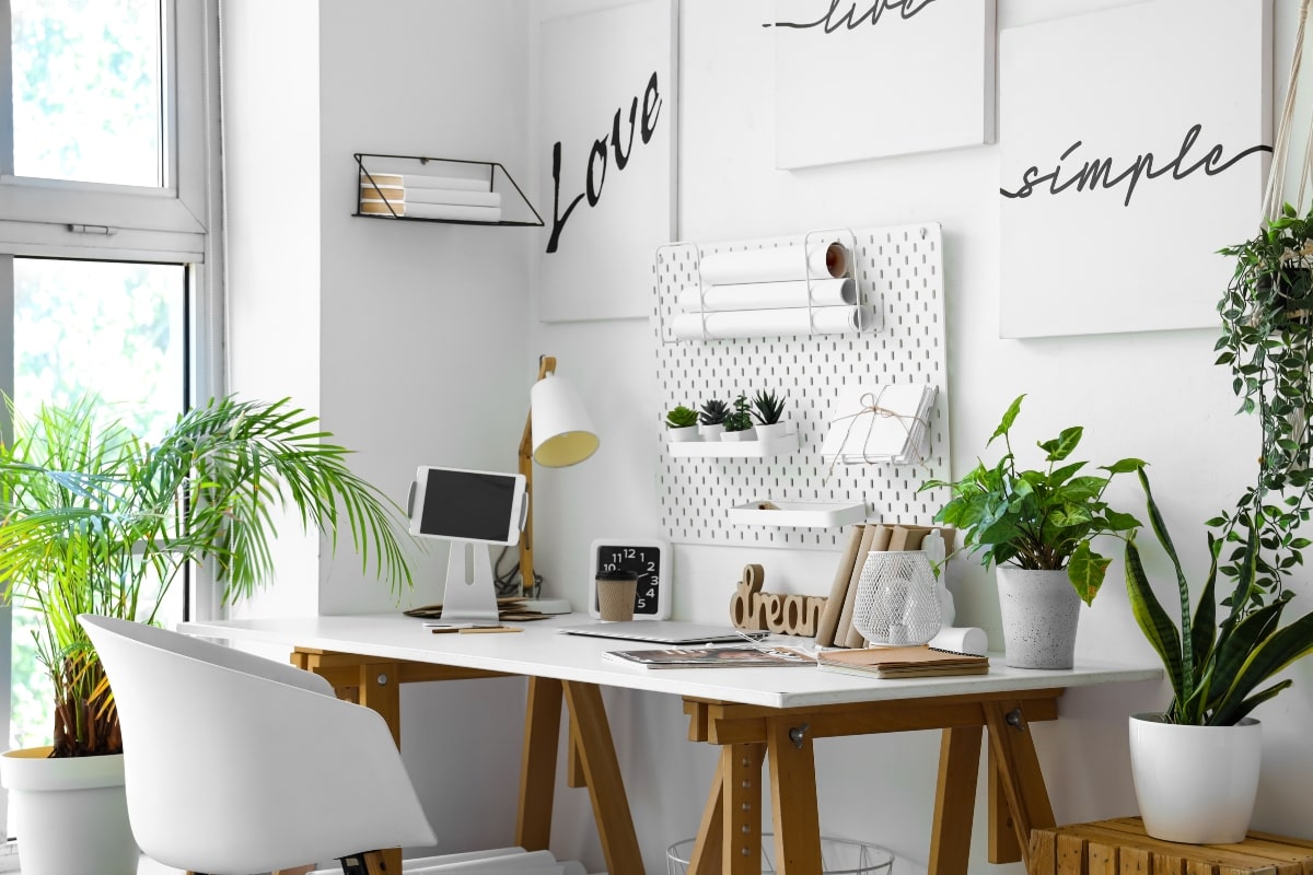Bright and organised home office setup with desk storage solutions, including a pegboard wall for holding supplies and shelves for plants and decor.