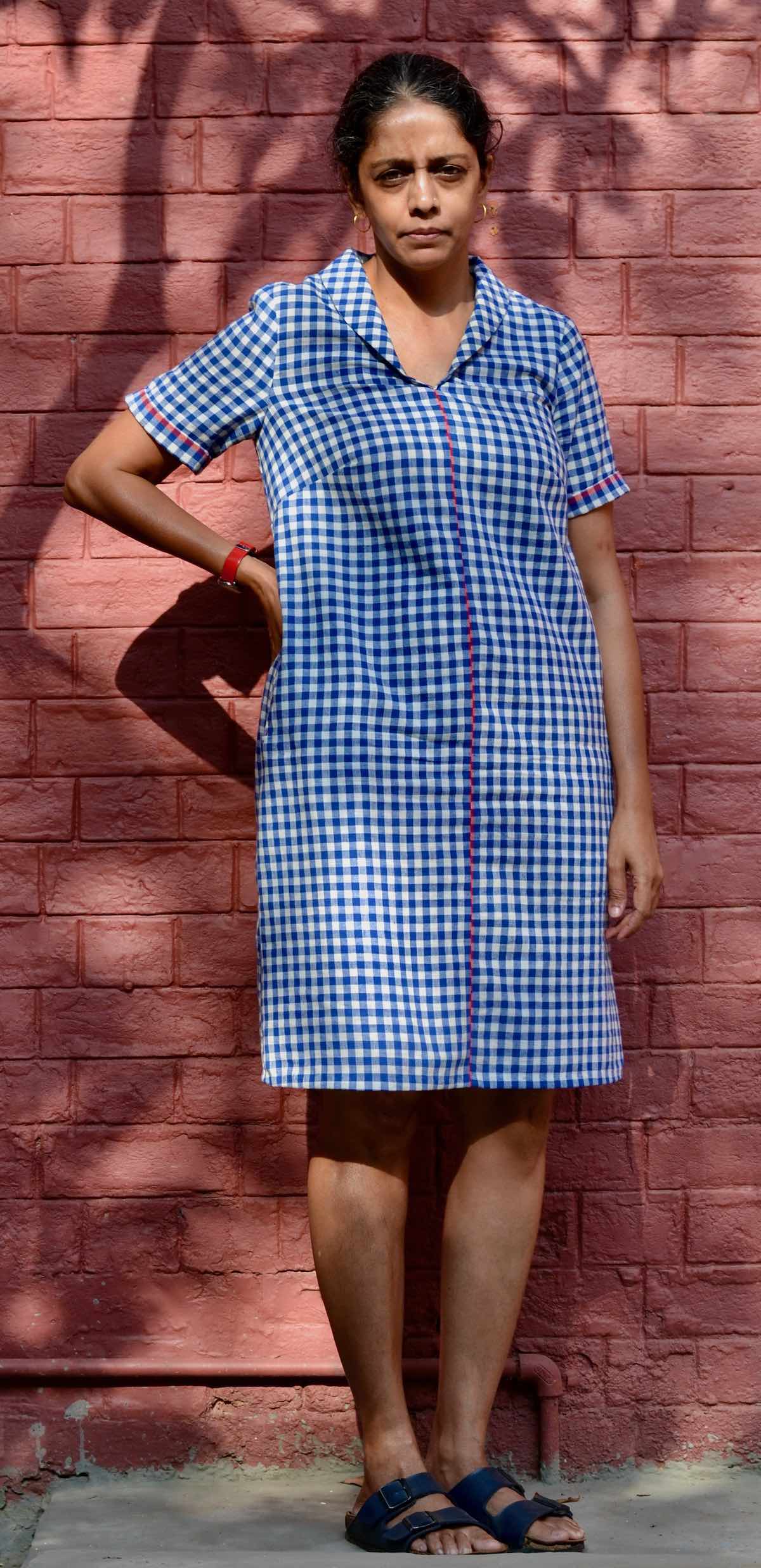 woman models short-sleeve blue gingham dress with shawl collar