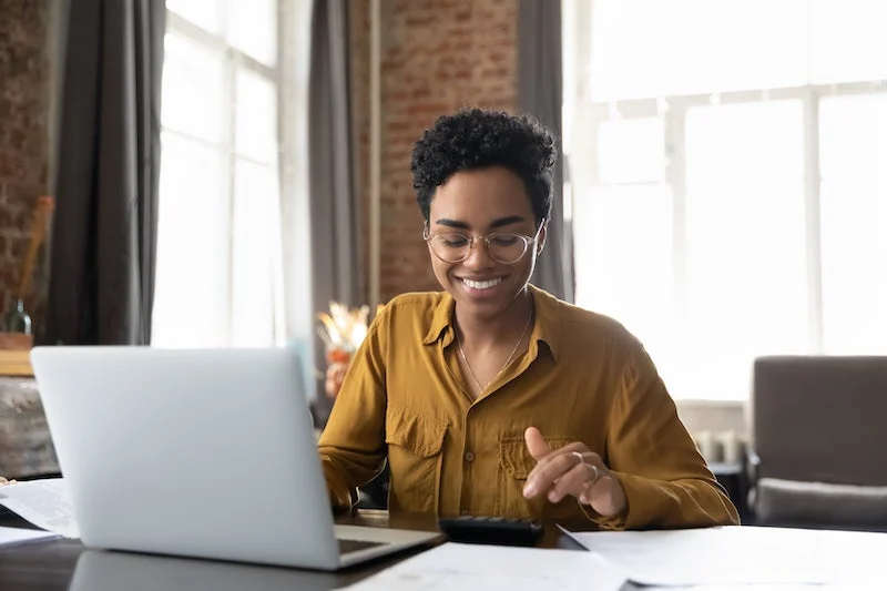 A woman is calculating her electricity bill smiling.