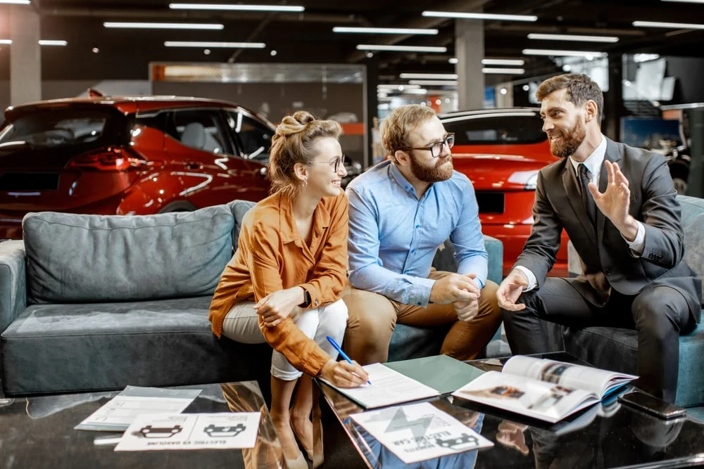 A car salesman explaining the ins-and-outs of an electric car to potential customers in the showroom.