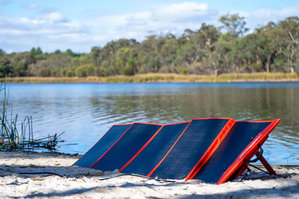 A solar blanket unfolded at the beach and ready to charge a battery