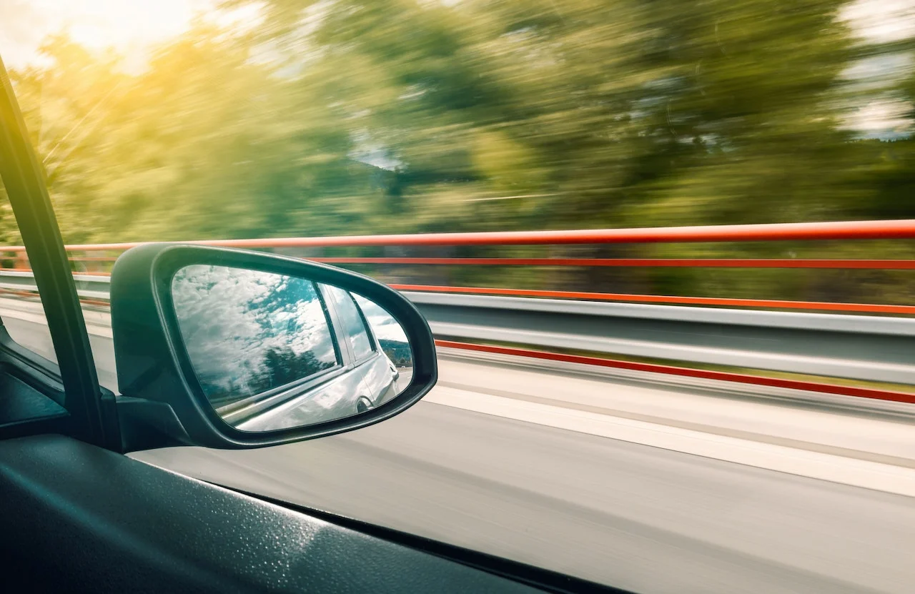 Car going fast on a road with the background of trees blurred.