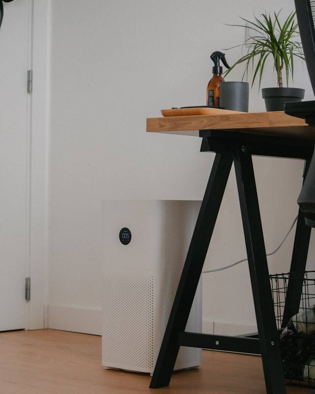 A modern home office with a white air purifier next to a desk, highlighting the Health Benefits of Air Purifiers for Dogs