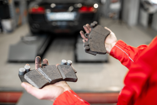 auto mechanic holding brake pads