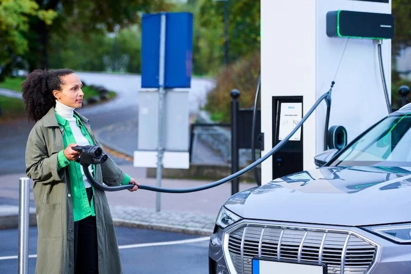 A woman is holding the charging cable that's connected to the cable management system of the EVBox Troniq Modular.