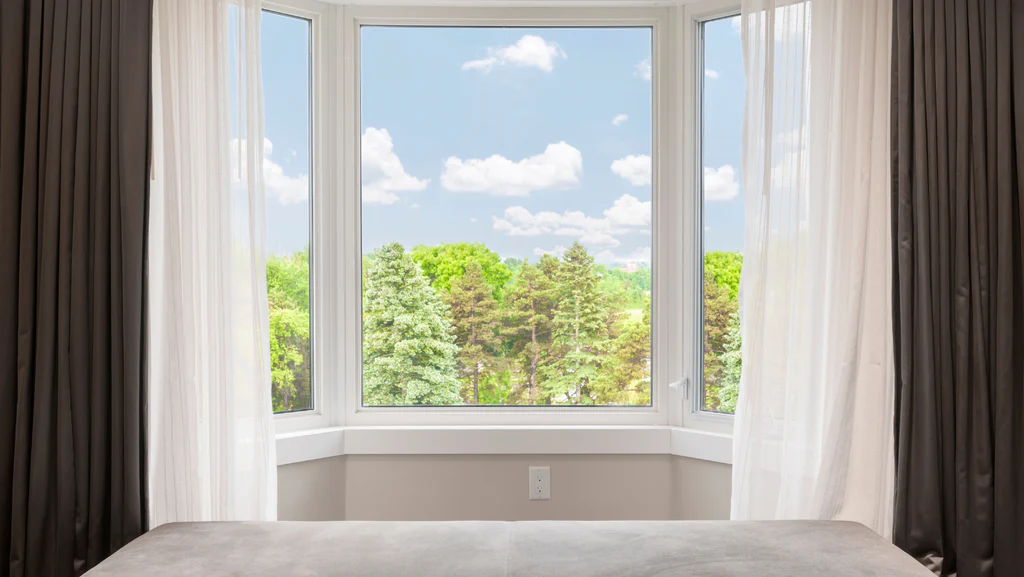 A bay window dressed with white curtains indoors