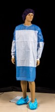 Disposable sugical gown material with reinforced piece