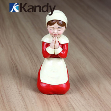A kneeling contemplative nun in white and red resin doll