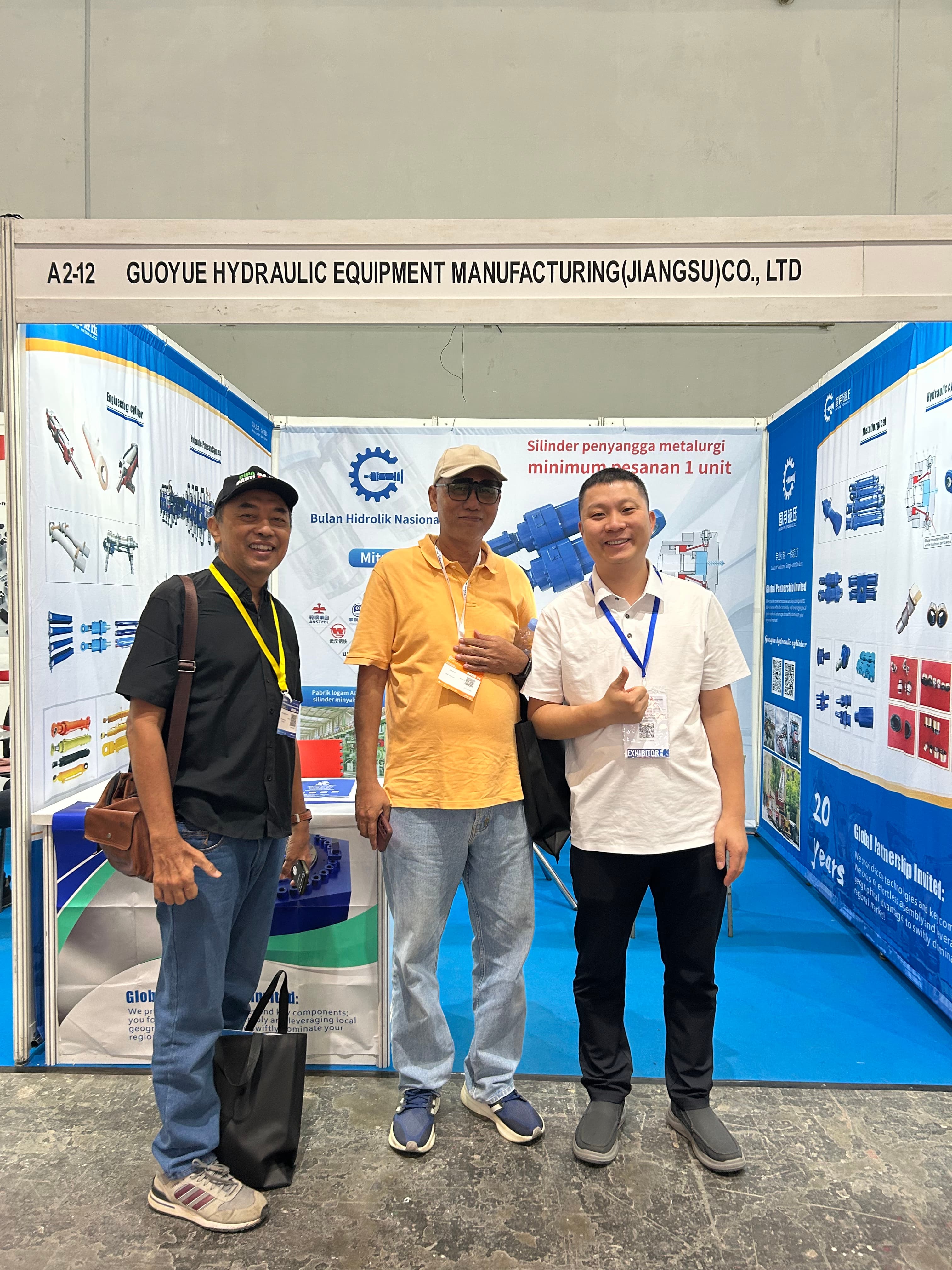 ジャカルタ産業展示会中にスタンド A2-12 で地元インドネシアの冶金技術者とポーズをとる Guoyue Hydraulics チーム。 Guoyue Hydraulics team posing with local Indonesian metallurgical engineers at Stand A2-12 during Jakarta industrial exhibition.