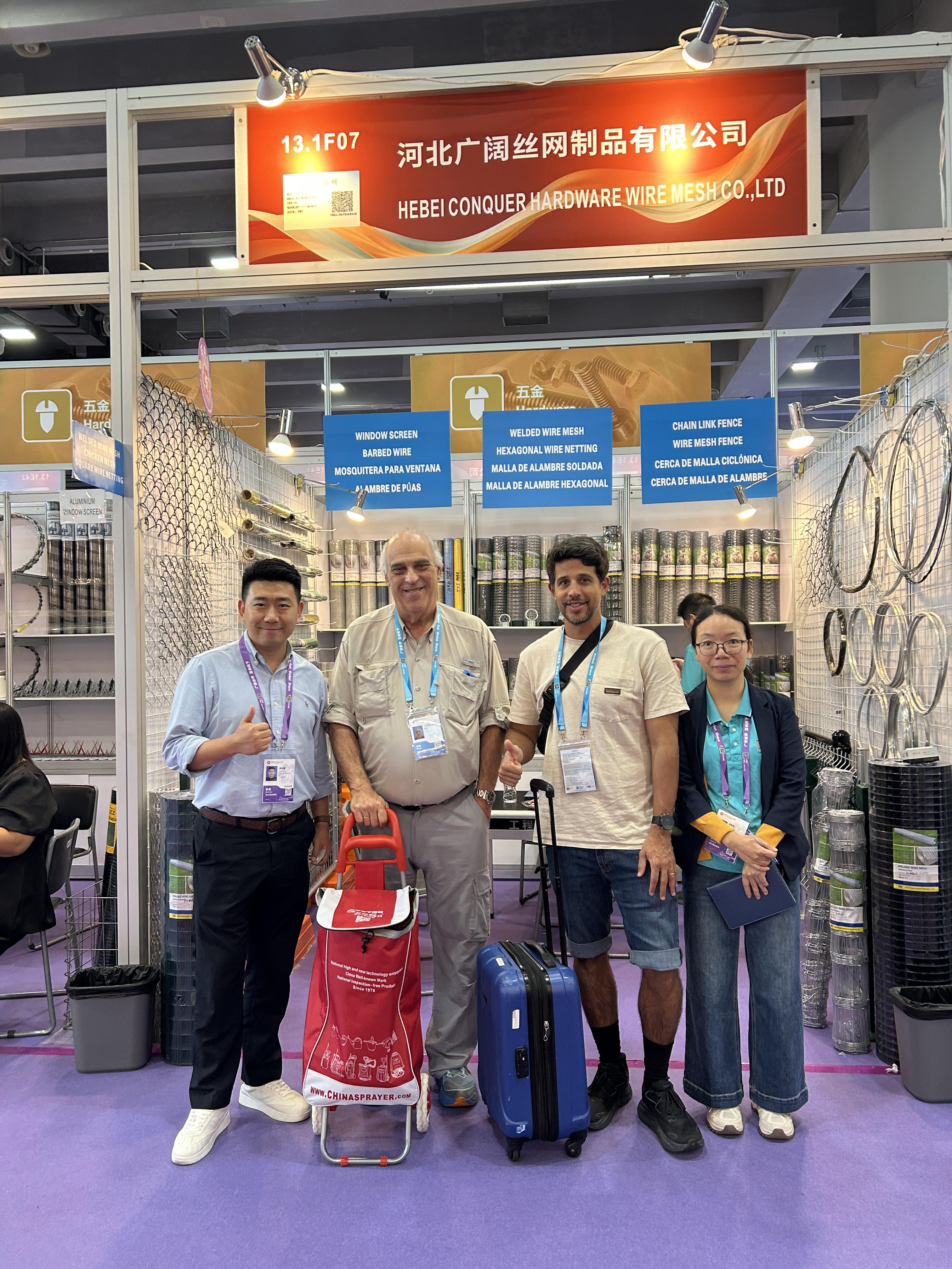 Maschendrahtzaun-Display | 140. Kantonsmesse Two buyers with ANJIA staff beside the chain link fence coils at Booth 13.1F07