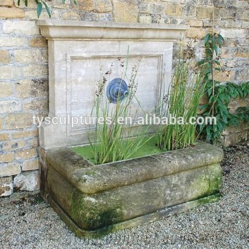 Antique outdoor landscape stone pump water fountain against wall