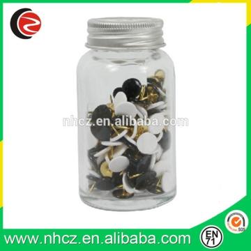 black and white gold plastic drawing pin in glass jar