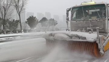 Snow brush and snow plow truck clearing road