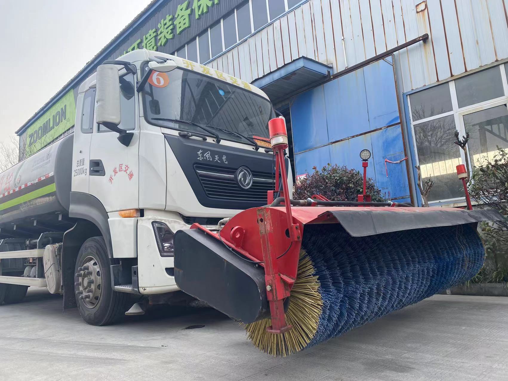 A snow plow brush mounted on the front of a car cl