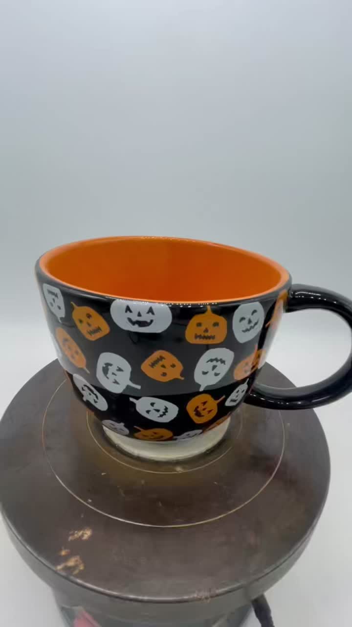 Linterna de calabaza de Halloween a través de una taza