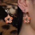 Des boucles d'oreilles conçues "Roaring Flower" sont appliquées