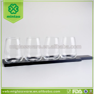 Clear stemless beer glass cup with black wooden rack and plate