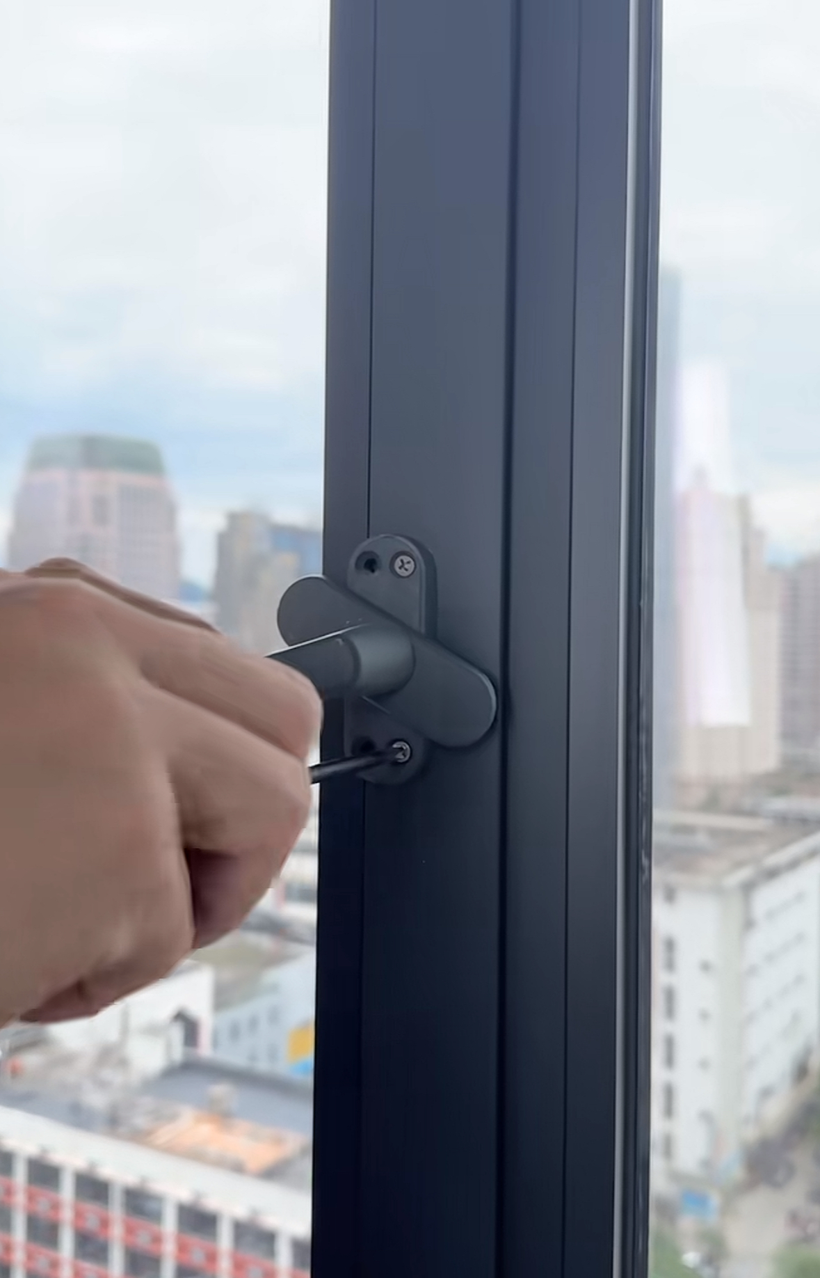 בעל מקצוע המתקין ידית חלון פרמיום שחור מט על מסגרת אלומיניום באמצעות מברג