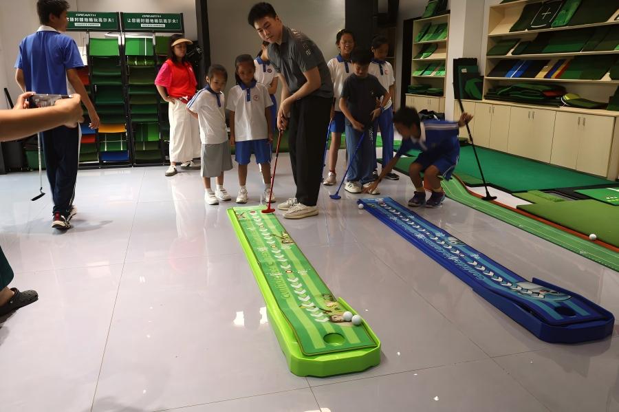 Children practicing golf putting during a community factory visit
