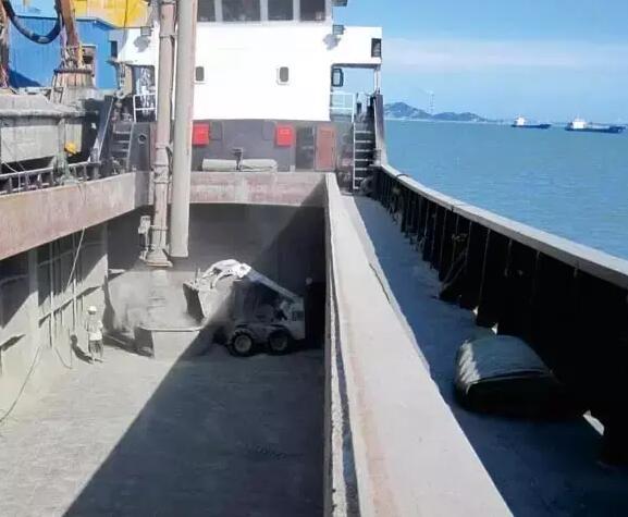 Bobcat skid steer loader cleaning residual bulk material in a ship hold
