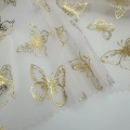 Tessuto tulle in poliestere con lamina di farfalle dorate
