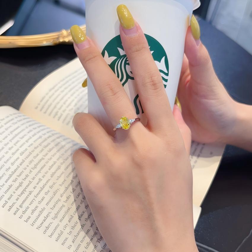 Matingkad na Yellow oval lab diamond trilogy ring na may mga bato sa gilid ng peras na ipinapakita sa kamay