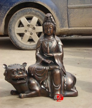 metal buddha statue sitting on tiger sculpture