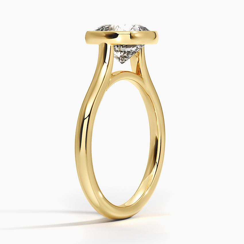 View ng profile ng nakataas na setting ng bezel sa isang plain gold band na nagbibigay-daan para sa isang flush wedding ring fit