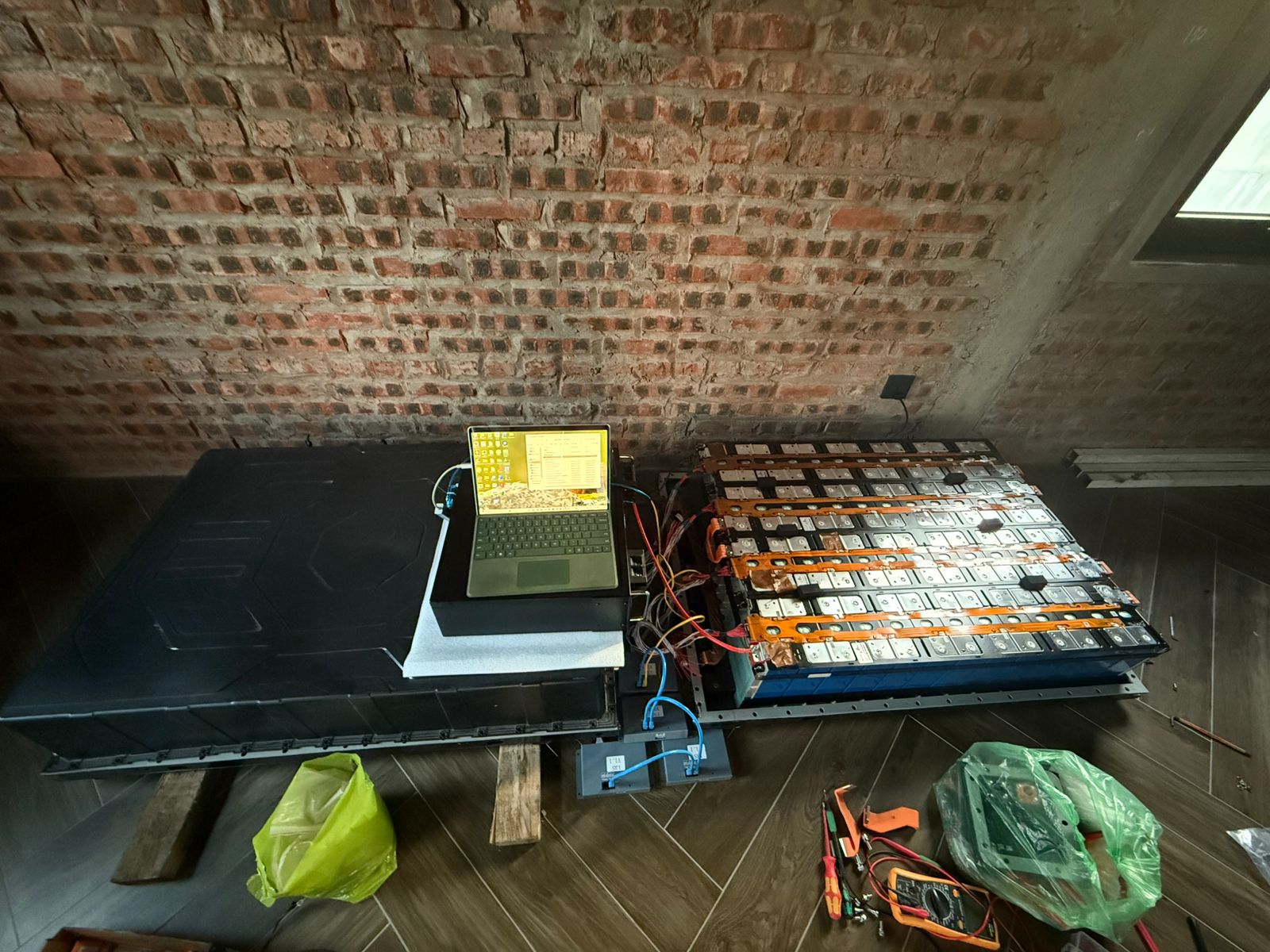 JBD engineering setup showing a laptop connected to the exposed 104S High Voltage commercial EV battery pack for BMS configuration and protection logic tuning in the workshop.