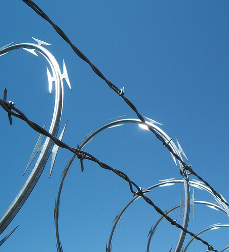 BTO-22 hot-dipped galvanized concertina razor wire installed on fence for perimeter security.