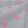 Beflockter Netzstoff aus 100 % Nylon mit rosa Schleife