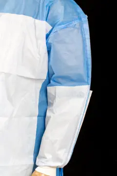 Disposable sugical gown material with reinforced piece