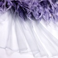 Tessuto di maglia in tulle di pizzo viola con piume glitterate