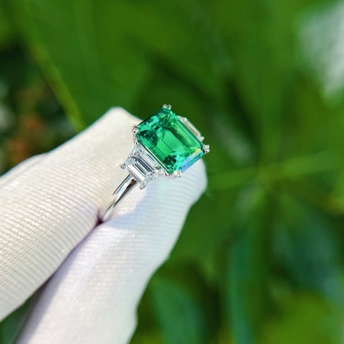 Platinový smaragdový zásnubní prsten ze 3 kamenů v laboratoři