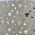 Tessuto in tulle di poliestere con stampa laminata di cuori dorati