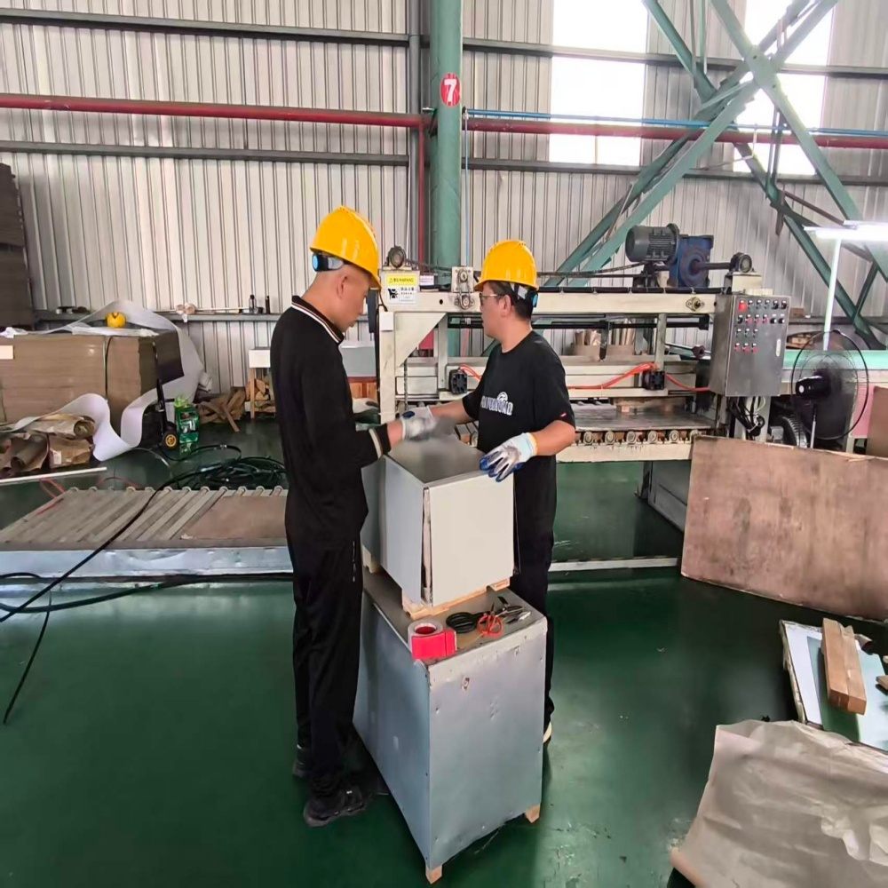 Two workers packaging a steel coil in factory.