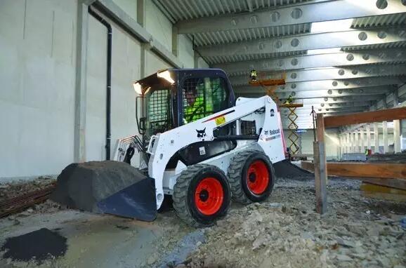 Bobcat T-series track skid steer loader leveling bulk coal in a ship hold