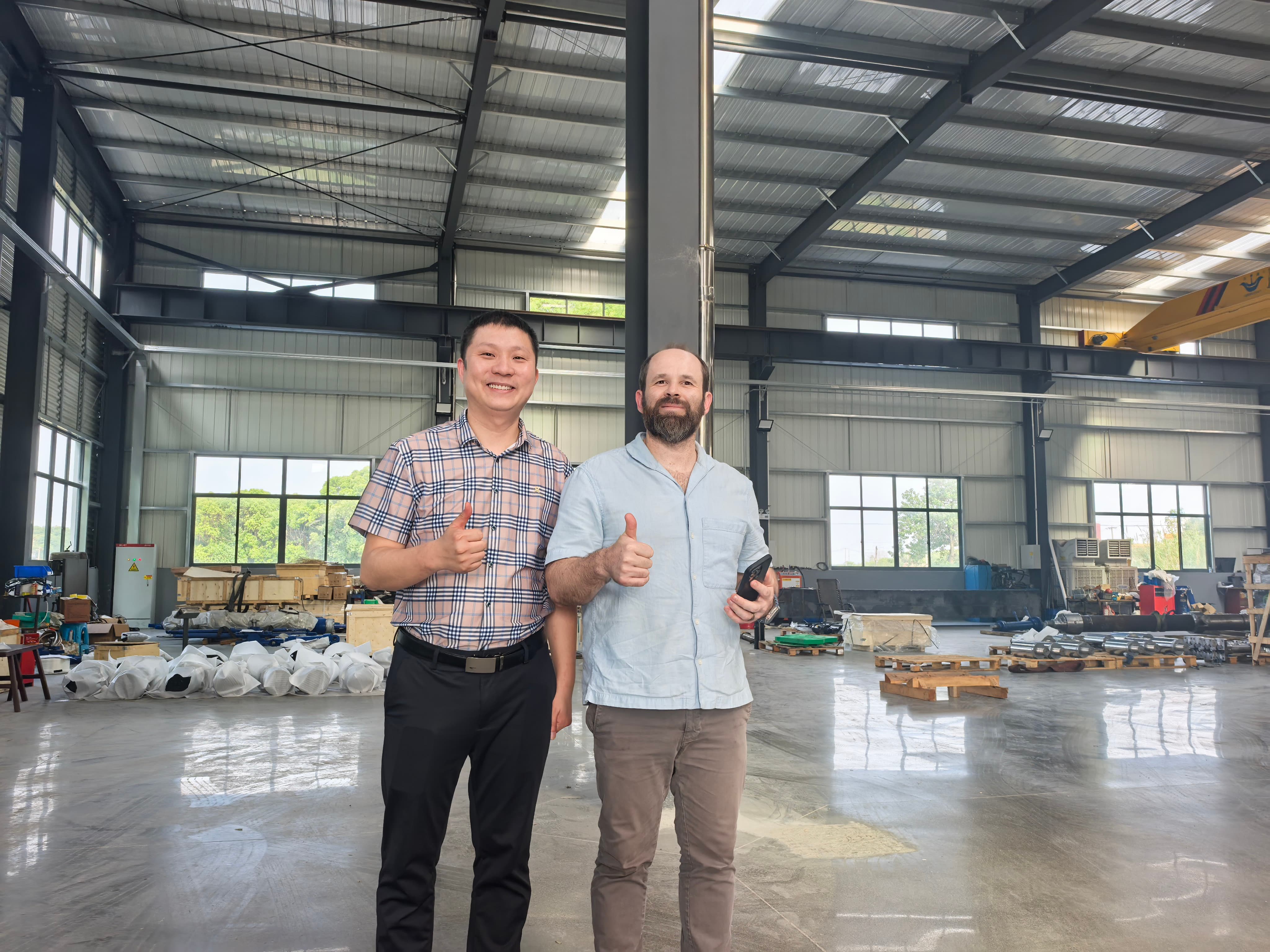 Guoyue Hydraulics manager and Brazilian client representative giving thumbs up after successful Factory Acceptance Test (FAT) of hydraulic cylinders.